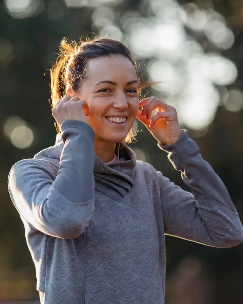 Woman smiling outdoors, adjusting her hair